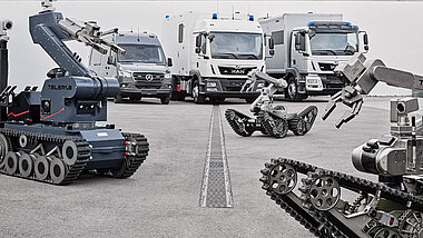 Unmanned vehicles with trucks and vans in the background