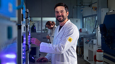 A man in an ESD coat stands in front of 3D printers