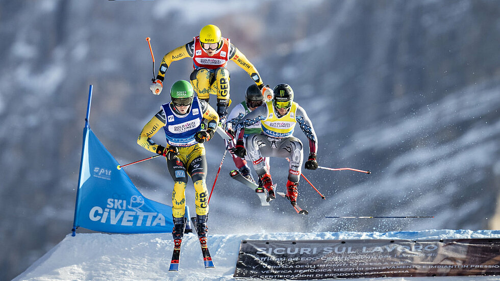 3 Skicrosser in der Gruppe im Sprung