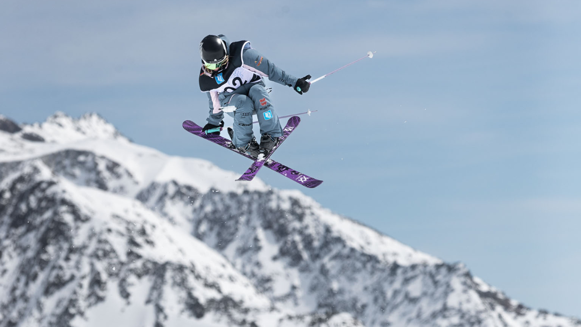 Freeskierin Muriel Mohr beim Springen im Hintergrund die schneebedeckten Berge